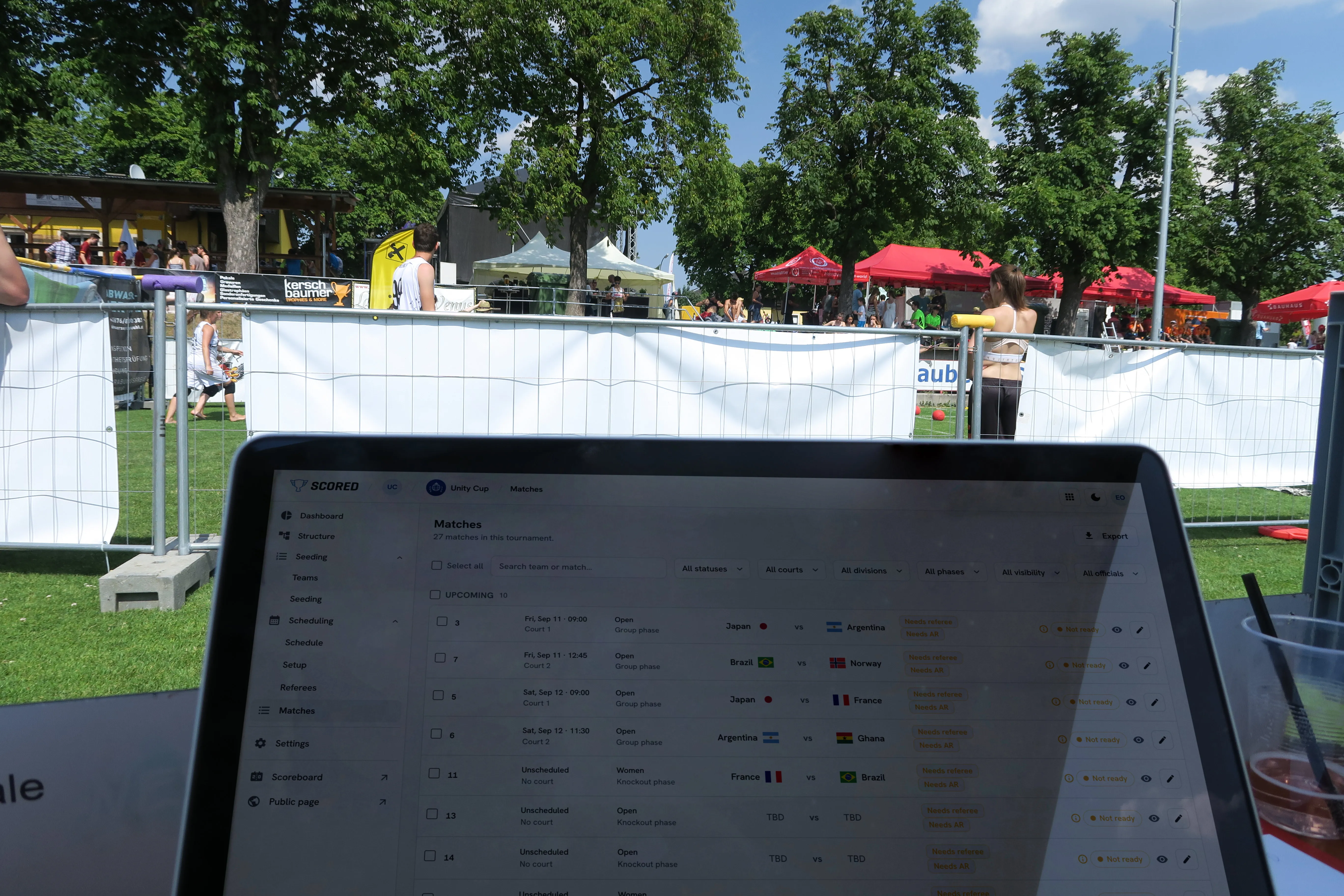 An organizer viewing the matches list on a laptop at an outdoor tournament